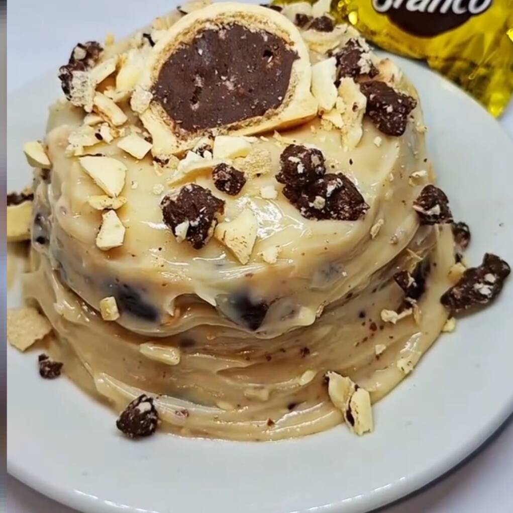 Massa caseira super fofinha e bem molhadinha, coberta por um vulcão de brigadeiro cremoso feito com cacau 50%, finalizado com recheio por fora de brigadeiro de Ouro Branco e pedaços generosos de bombom. Chocolate, cremosidade e crocância na medida certa… impossível comer só um pedaço. ✨