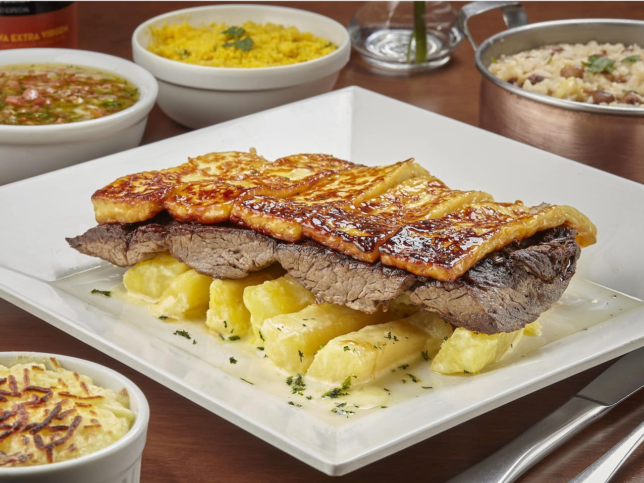 450g de carne de sol de filé mignon sobre uma cama de macaxeira cozida com manteiga da terra e coberta com queijo coalho grelhado. Acompanha melaço de cana, porção de baião de dois, vinagrete e farofa.