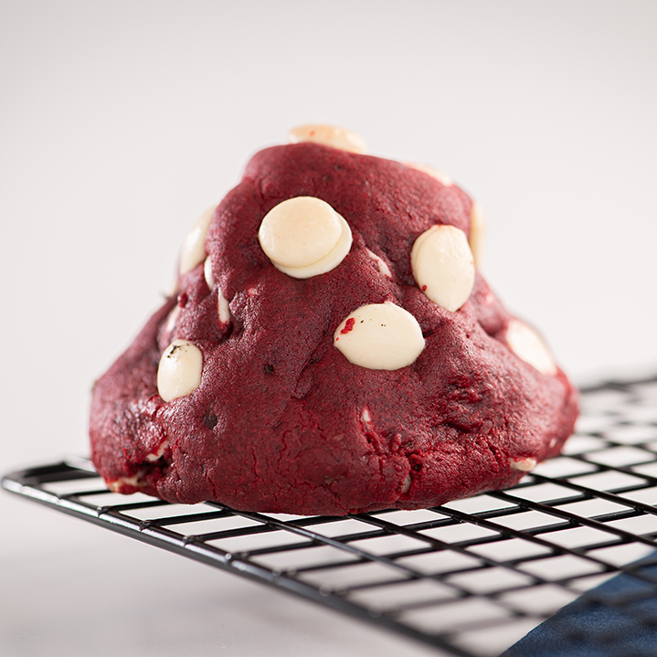 Massa de baunilha e cacau, gotas de chocolate nobre branco e recheio de ganache de cream cheese com geleia artesanal de frutas vermelhas.