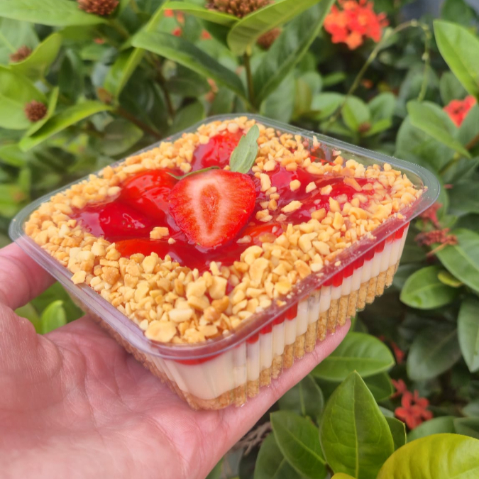 Delícia de Morango com Creme Belga e Amendoim Uma sobremesa montada em camadas de puro prazer! Base crocante de bolacha triturada, recheada com o nosso autêntico e sedoso Creme Belga artesanal. Adicionamos morangos frescos selecionados e uma camada de geleia artesanal da fruta para intensificar o sabor. O toque final fica por conta do amendoim triturado, que traz a crocância perfeita para cada colherada.