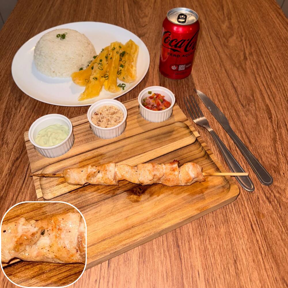 Espeto de peito de frango acompanhado por arroz, mandioca, vinagrete, farofa crocante e molho verde.