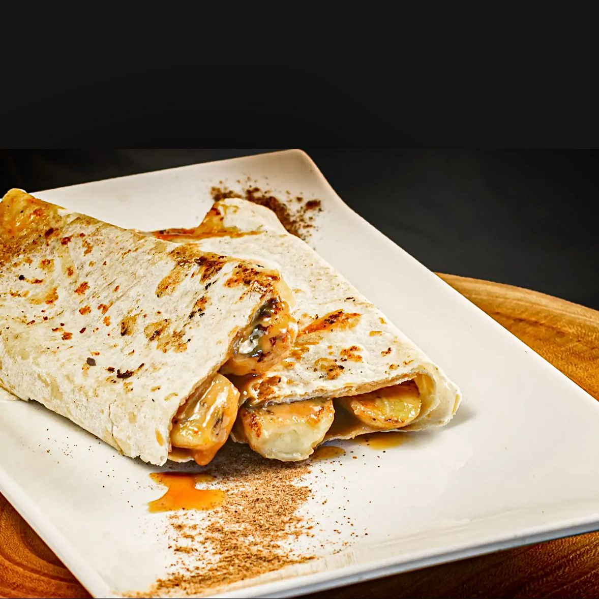 Pão sírio de 25cm recheado com doce de leite cremoso, fatias de banana e chantilly, formando um irresistível sabor de banoffee.