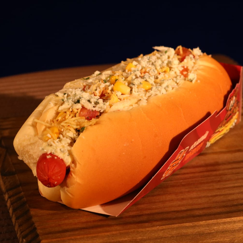 Pão, salsicha, molho de tomate, molho de queijo gorgonzola, molho cheddar, maionese, ketchup, mostarda, molho mil ilhas, tomate, milho, ervilha, salsa, queijo parmesao e batata palha.