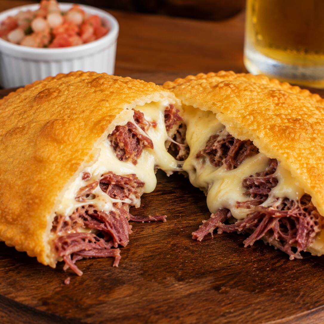 Carne seca desfiada e bem temperada, combinada com Catupiry cremoso, criando um recheio marcante, suculento e irresistível. A intensidade da carne seca encontra a cremosidade do Catupiry, tudo envolvido em uma massa sequinha, crocante e douradinha. 🤤