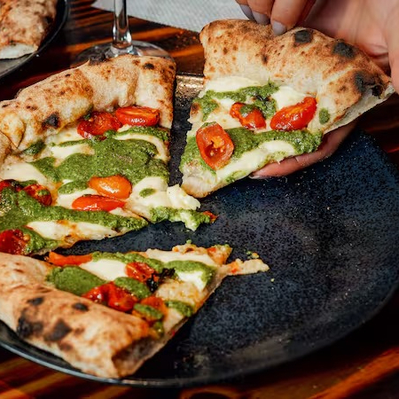 Massa de fermentação natural, molho pesto, mussarela de búfala artesanal e tomate cereja confitado Obs: por padrão, a pizza é enviada inteira (não fatiada) para garantir uma melhor conservação e mantê-la quente por mais tempo (além de facilitar caso você queira reaquecê-la no forno ao recebê-la). Se preferir que enviemos a pizza cortada em fatias, favor especificar na observação do pedido ;)