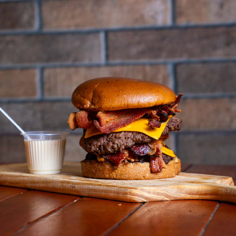Pão pretzel, 2 smash 90 gr, bacon duplo, queijo cheddar duplo, maionese da casa, molho especial . O 'Duplo Smash Bacon' é uma obra-prima da categoria 'Smash Burger'. Este prato é uma explosão de sabores, composto por um pão pretzel crocante e aveludado, harmonizado com duas suculentas carnes smash de 90 gramas cada, meticulosamente temperadas. Envolvido em uma generosa camada de bacon duplo, irres