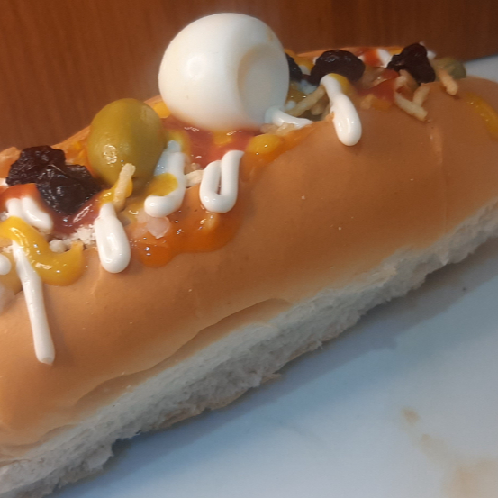 Pão, Linguiça, milho, ervilha, maionese, ketchup, Molho cru (tomate, cebola, pimentão), molho tomate (caldinho), azeitona, ovo de codorna, queijo ralado, uva passas e batata palha