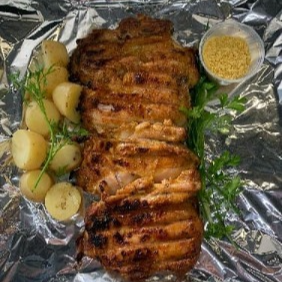 Filé de coxa com sobrecoxa na brasa, acompanhado de uma porção de batata no molho de alho e farofa.