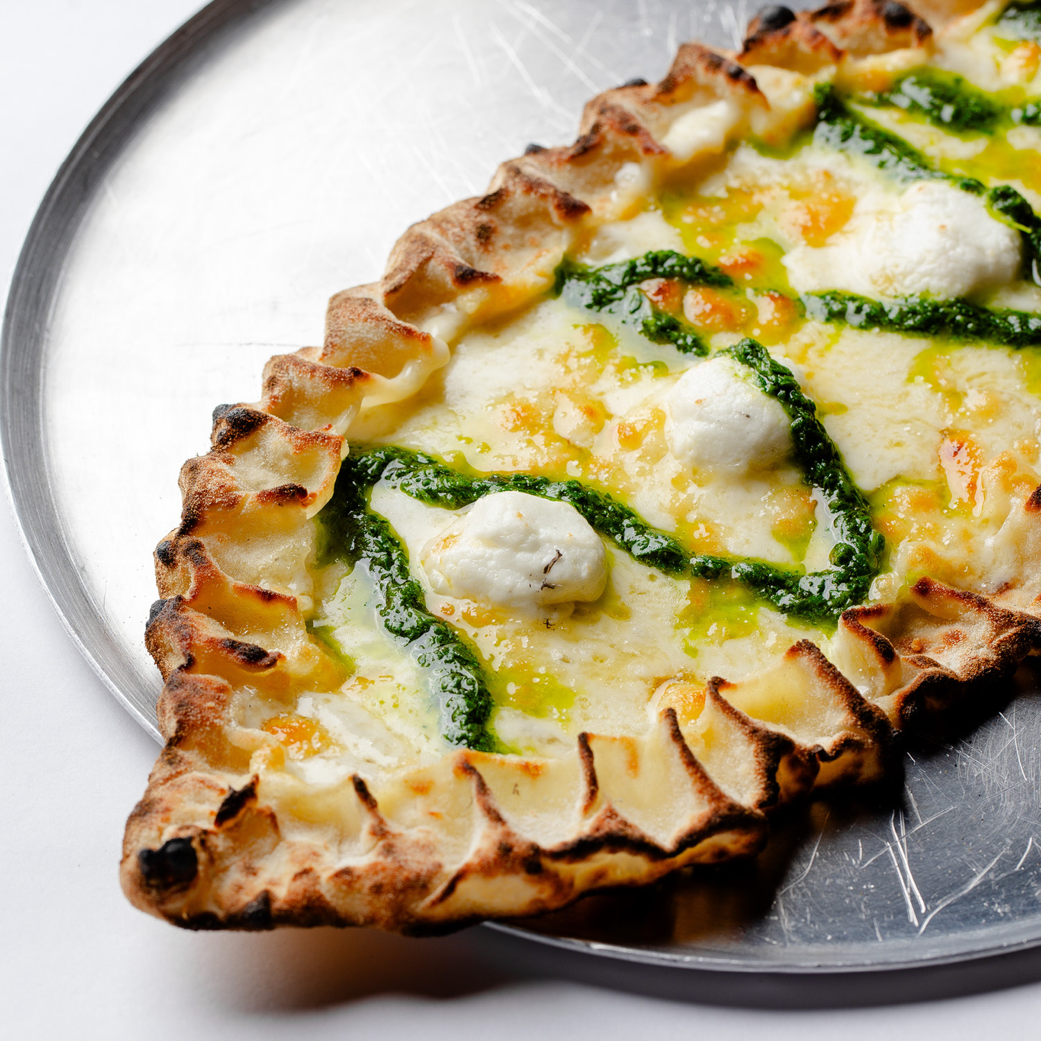 ESFIHA TURCA EM FORMATO DE BARCA, COM MUSSARELA, QUEIJO DE CABRA E PESTO DE ESPINAFRE COM ALHO. VEGETARIANA. CONTÉM GLÚTEN. CONTÉM LACTOSE.