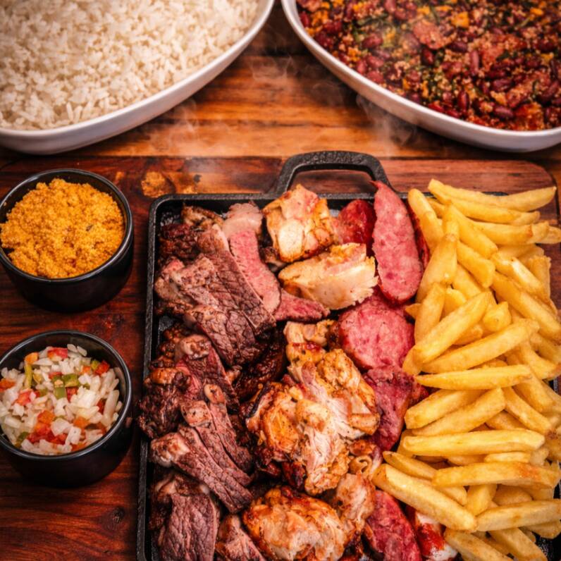 200g contra filé, 200g filé sobrecoxa na mostarda, 200g linguiça de pernil, 300g batata frita, feijão tropeiro, arroz branco, molho vinagrete e farofa da casa e 2 heinekens 330ml longNeck.