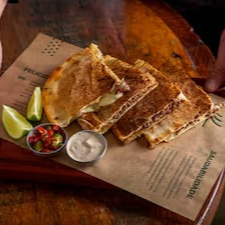 Pão pita tostado com carne bovina, muçarela, taratour tomate assado, acompanha picles de pepino.