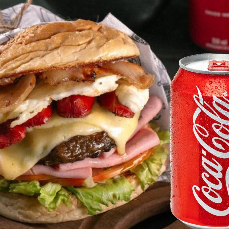 Hambúrguer Bovino, queijo, bacon, ovo, salsicha, alface, tomate, milho e batata palha, acompanhado de refrigerante lata. Peça agora! + Coca-Cola Lata 350ml