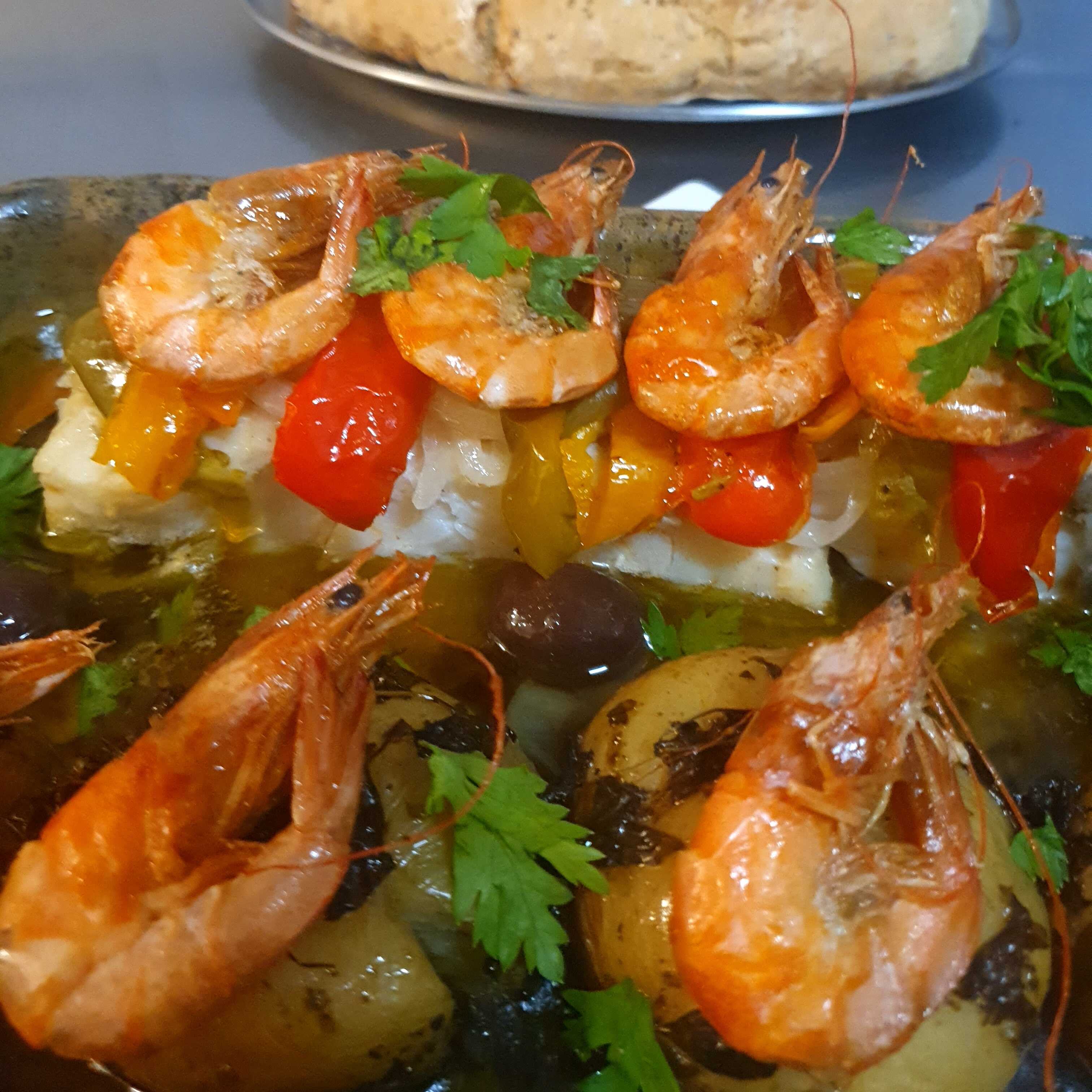 Lombo de bacalhau com cebola, pimentões, batata ao murro e camarões, regado com azeite e cozido no forno. Acompanha pão caseiro. Serve 1 pessoa