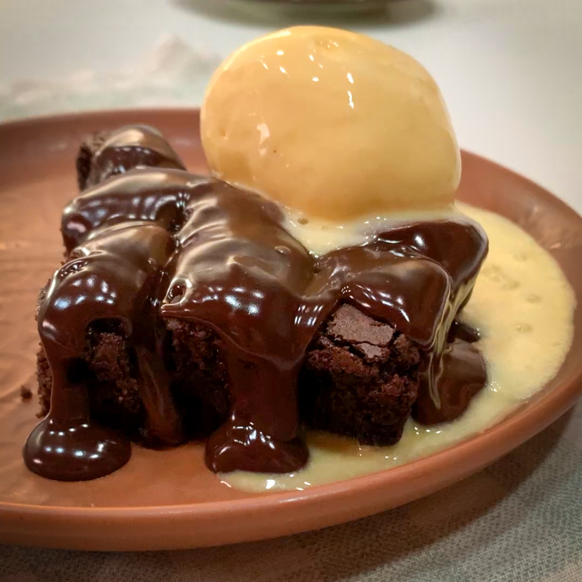 Brownie quentinho com generosa calda de chocolate ao leite.