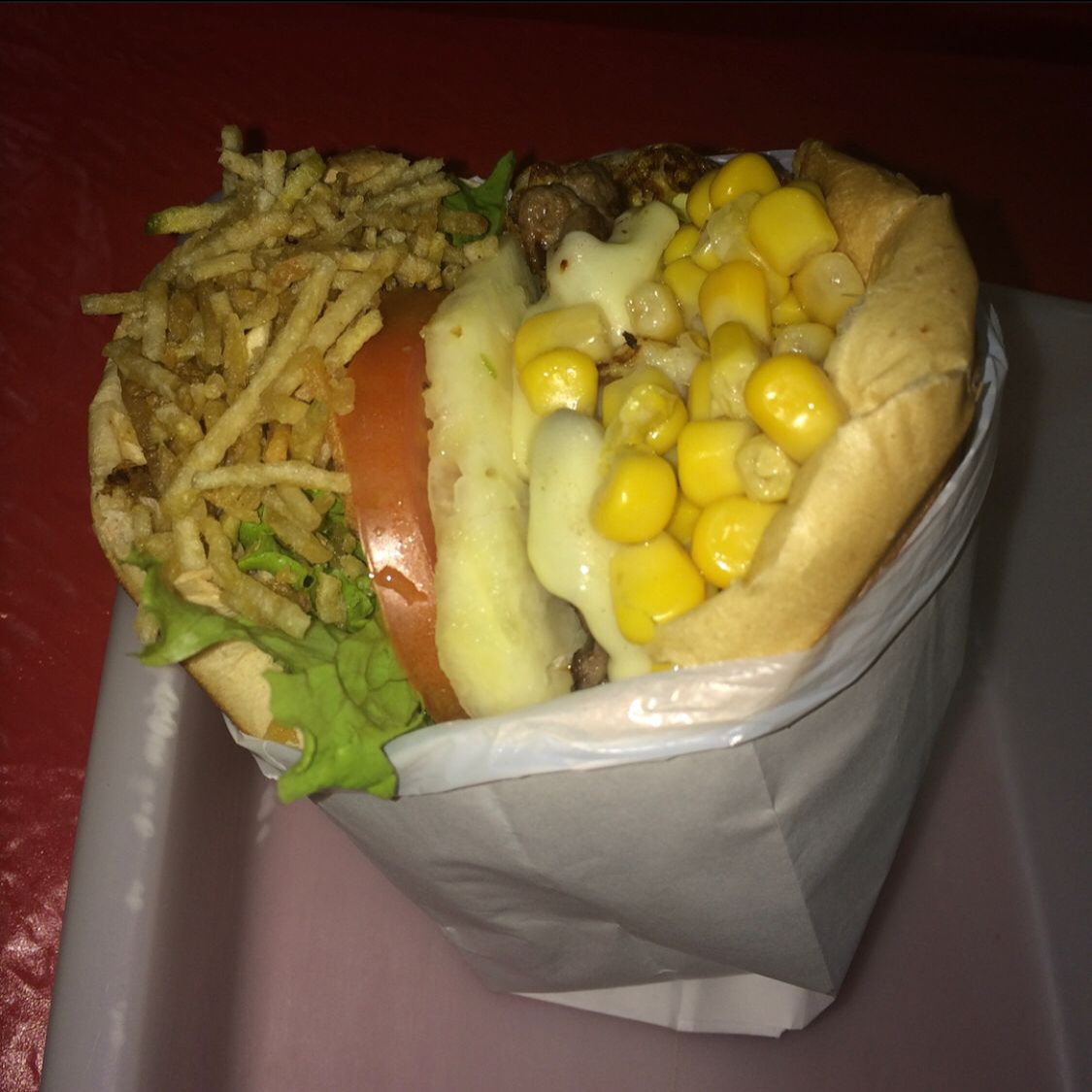 Pão, hamburguer, muçarela, tomate, alface e milho.