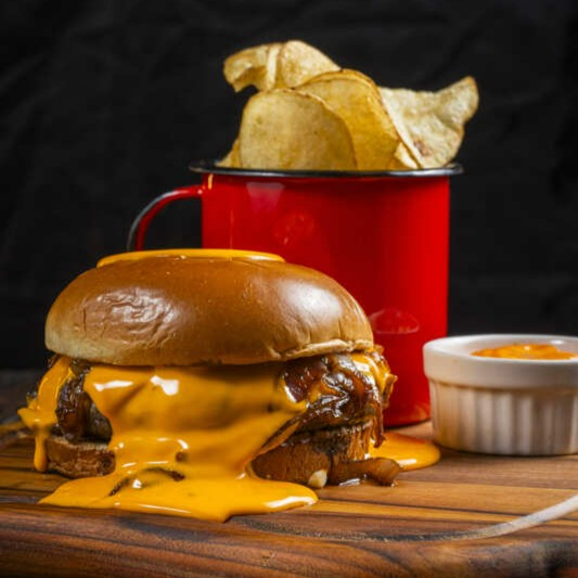 Um sabor que encanta! O Cheddar Burger é a união perfeita entre um hambúrguer Angus suculento e o irresistível sabor do queijo cheddar. Com um molho cheddar caseiro e cebola caramelizada, servido em um pão brioche leve, cada mordida é uma viagem ao paraíso dos sabores!