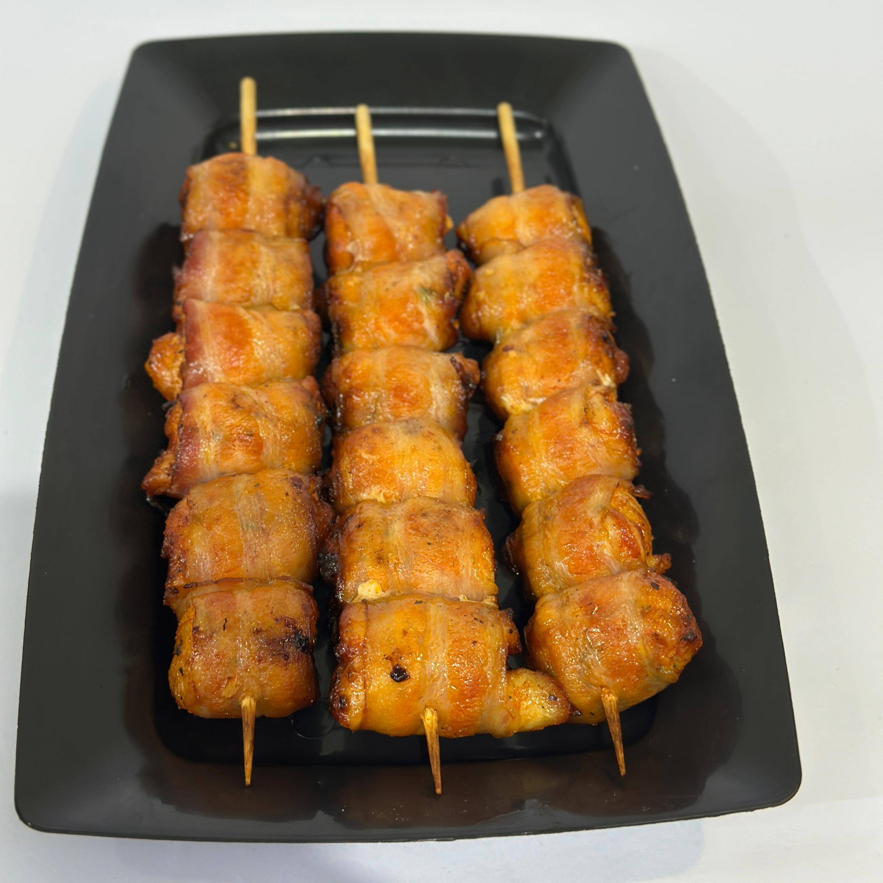 Peito de frango enrolado no bacon e assado na brasa.