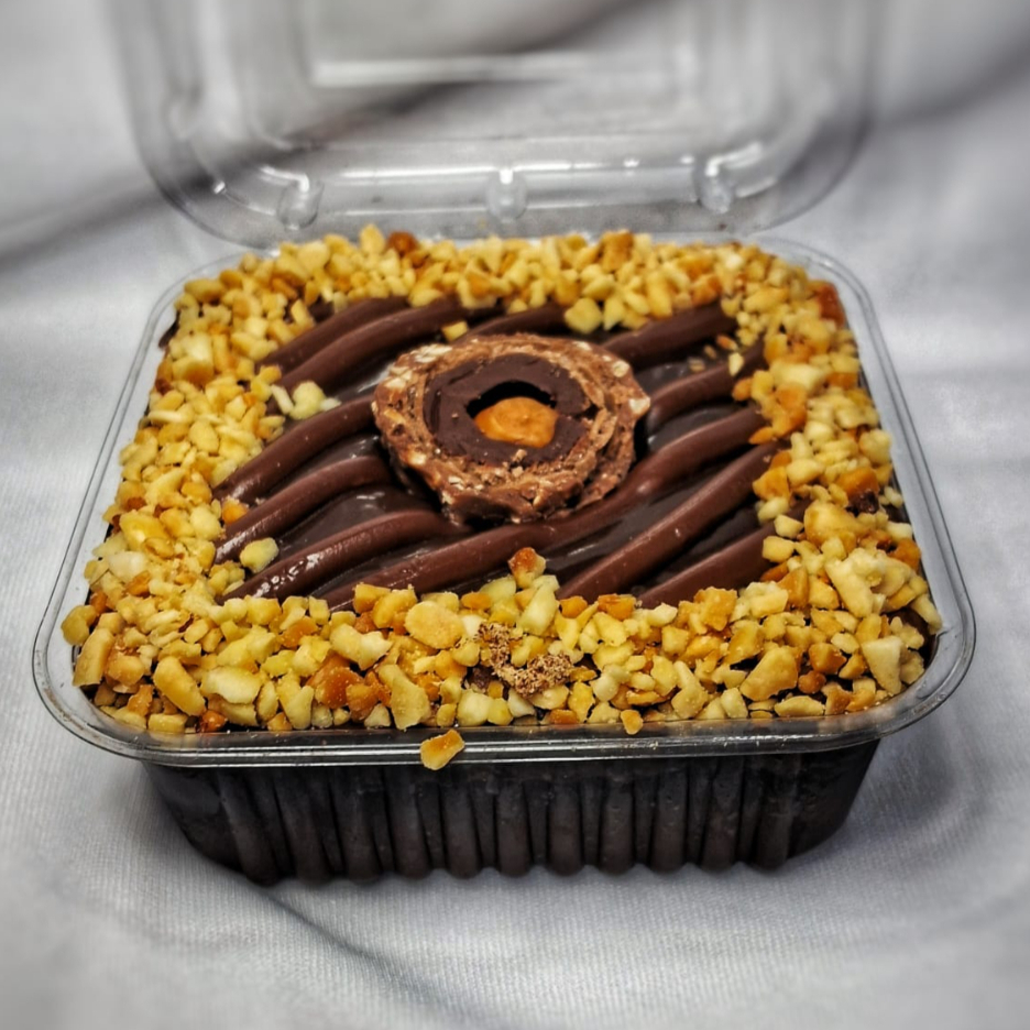 Bolo de chocolate 50% cacau molhadinho com calda de chocolate, recheio de brigadeiro 50% cacau com riscos de Nutella, decorado com amendoim triturado e meio Ferrero Rocher no centro.