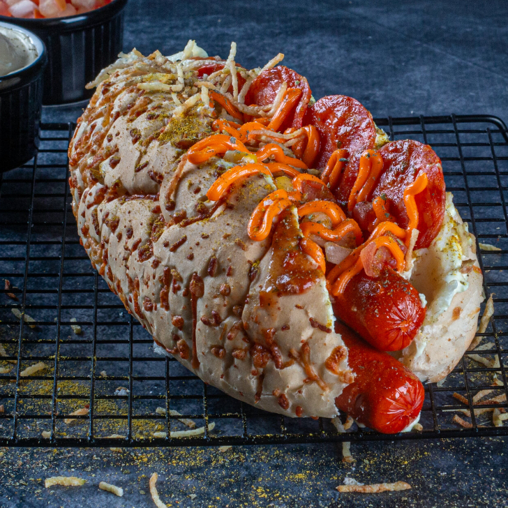 2 salsichas hot dog (ou troque sua salsicha), cheddar ou requeijão, milho, vinagrete, batata palha, maionese, purê, orégano, curry e coberto por uma deliciosa crosta de parmesão. *Ao escolher a Salsicha Húngara (picante), será servida apenas uma unidade, por se tratar de uma salsicha grande e bem servida.