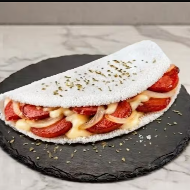 Tapioca recheada com calabresa acebolada e muçarela derretida, preparada na hora. Uma opção irresistível para quem ama um recheio bem caprichado.