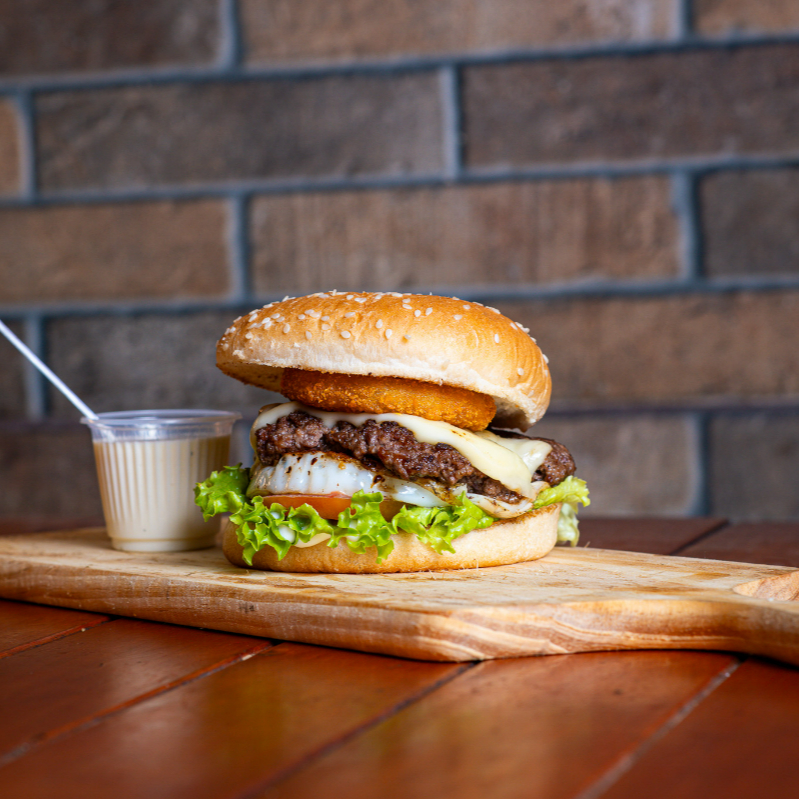 Pão gergelim, smash 90gr, anéis de cebola, ovo, queijo mussarela, alface, tomate, maionese da casa, molho especial . Apresentamos o 'Bobo da Corte', um ícone da categoria Smash Burguer. Deguste a harmonia perfeita entre um suculento smash de 90gr, envolvido por um pão de gergelim fresco e crocante. Desfrute da explosão de sabor proporcionada pelos anéis de cebola fritos à perfeição, realçada pela