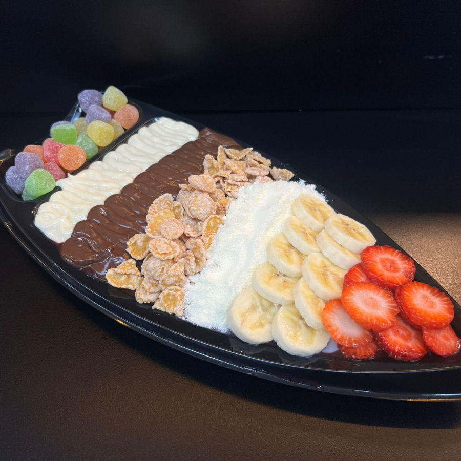 Barca M Promocional 02 Uma verdadeira tentação em forma de açaí! 🤤 São 400g de açaí premium super cremoso, acompanhados de 8 complementos que deixam cada colherada ainda mais especial: jujuba colorida, chocolate branco, chocolate ao leite, sucrilhos crocantes, leite ninho, banana, morango fresquinho e aquele toque irresistível de leite condensado. Uma combinação perfeita entre cremosidade, crocância e doçura, formando uma barca generosa de aproximadamente 650g de puro prazer! 😋✨ Ideal pra quem quer se presentear ou dividir um momento delicioso!
