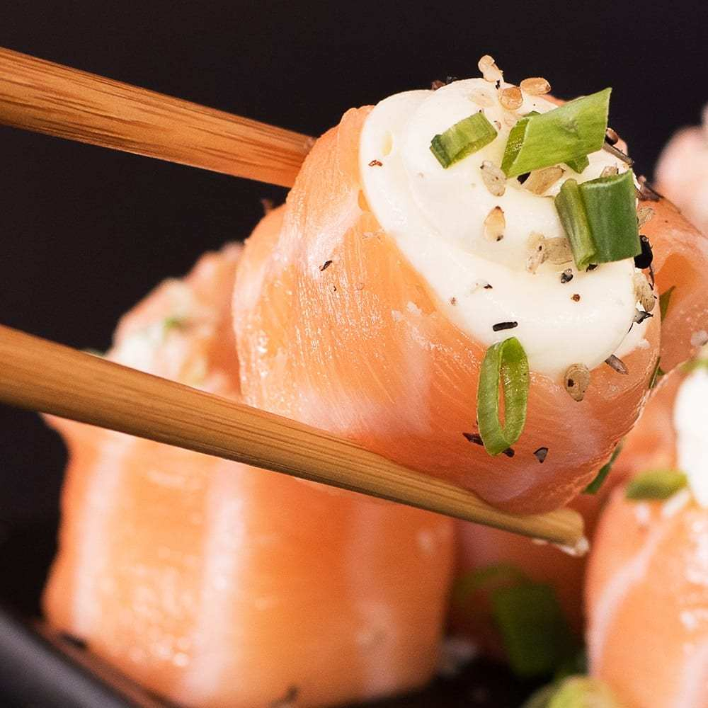 lâmina de salmão envolto do arroz preparado para sushi , com creamcheese no topo , finalizados com gergelim
