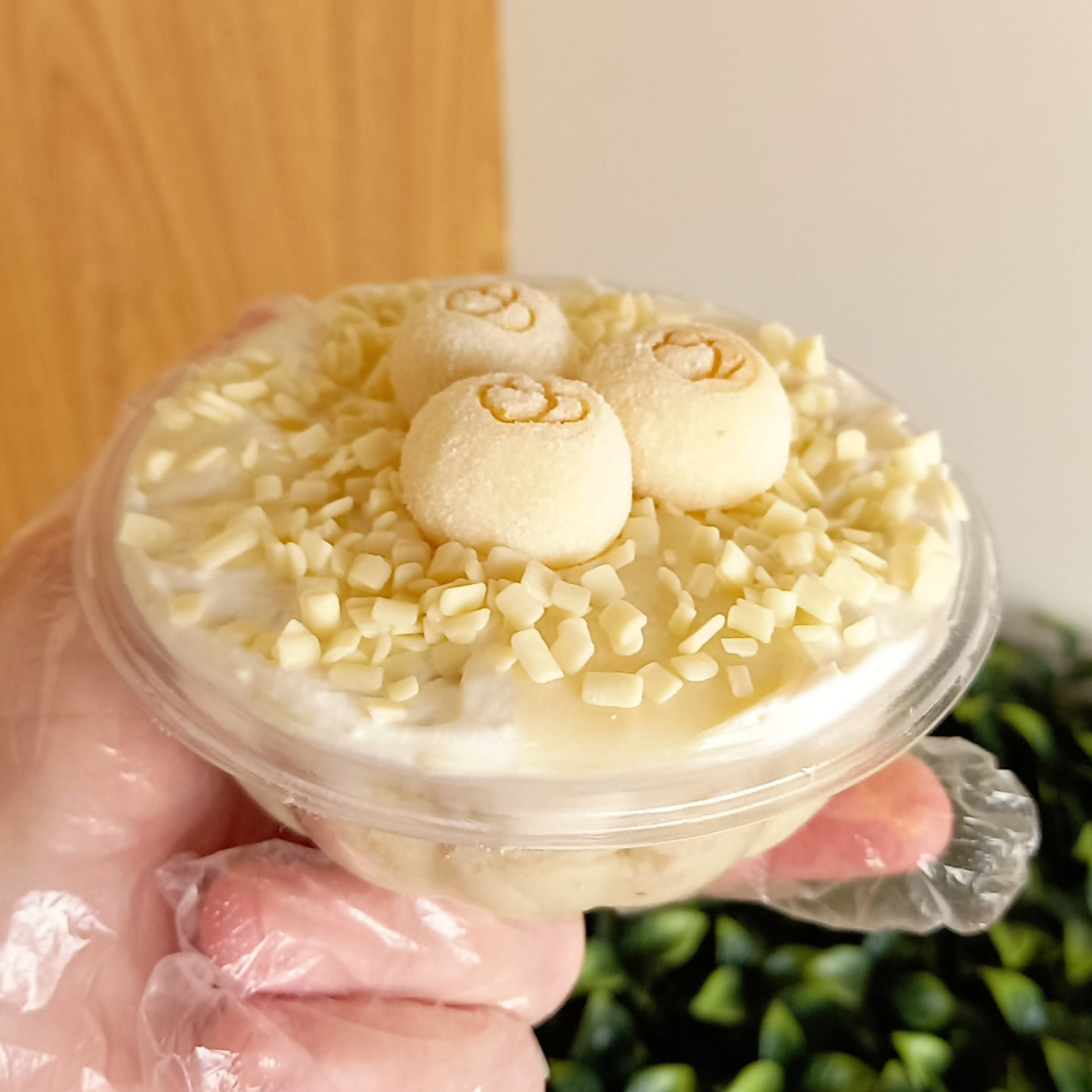 Bolo Branco molhadinho com recheio de Ninho cremoso, coberto com Granulado de Chocolate Branco Belga e docinhos Gourmet de Ninho.