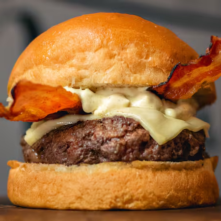Hambúrguer de 140g, queijo provolone derretido, duas fatias de bacon crocante e molho de bacon no pão brioche. Uma combinação irresistível de sabores defumados e suculentos!