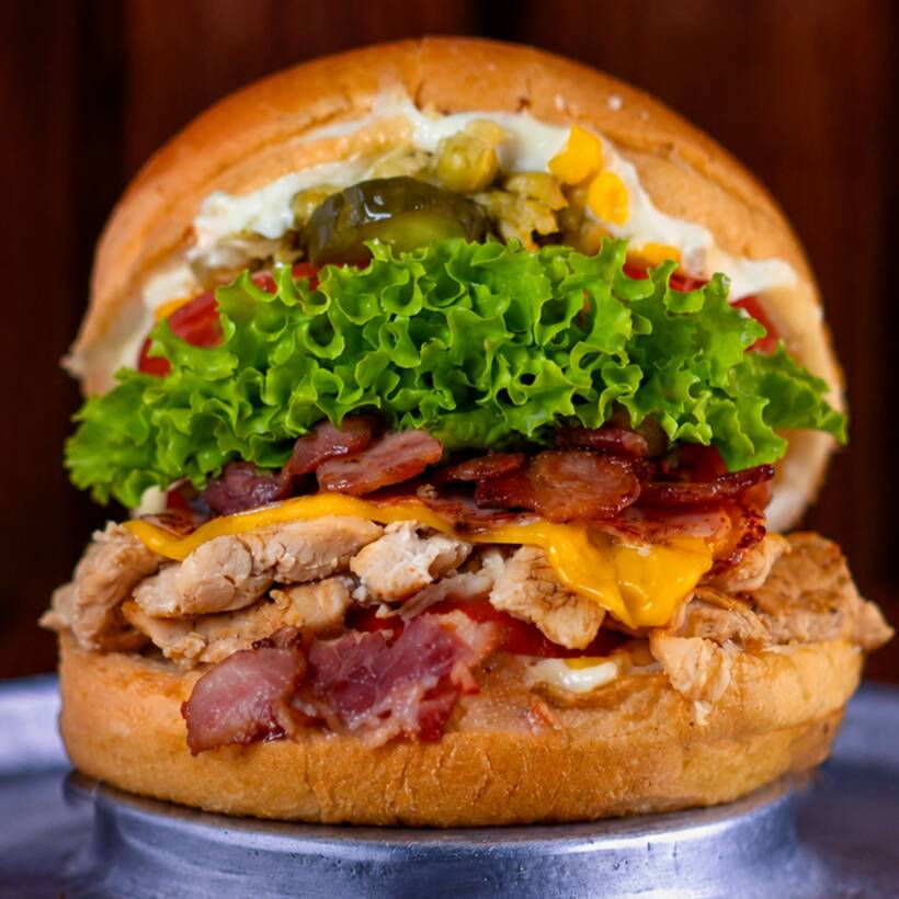 Pão macio com filé de frango grelhado, muçarela derretida, bacon crocante, requeijão cremoso, alface americana, tomate, milho verde e batata palha. Completo e delicioso.