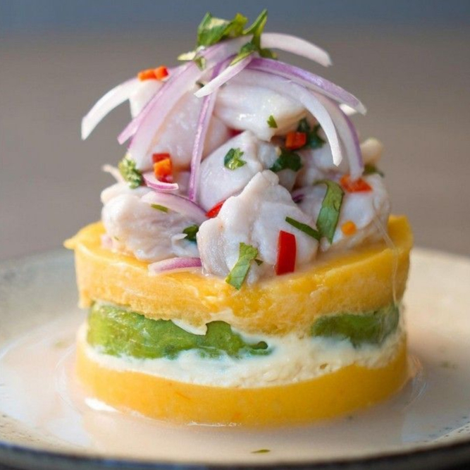 Batatas amassadas, temperadas com pimenta peruana (sem ardência), recheio de abacate e coberto com ceviche de peixe