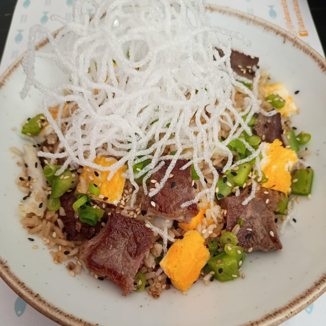 Cortes de filé mignon com arroz frito em molho shoyu, pimentão, cebolinha, tortilha de ovo e óleo de gergelim.