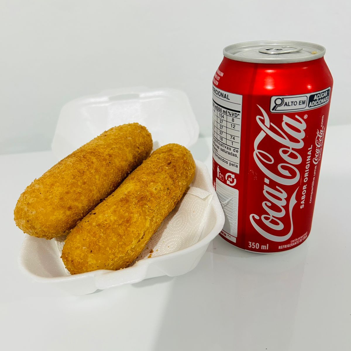 dois enroladinhos de salsicha com uma coca lata.