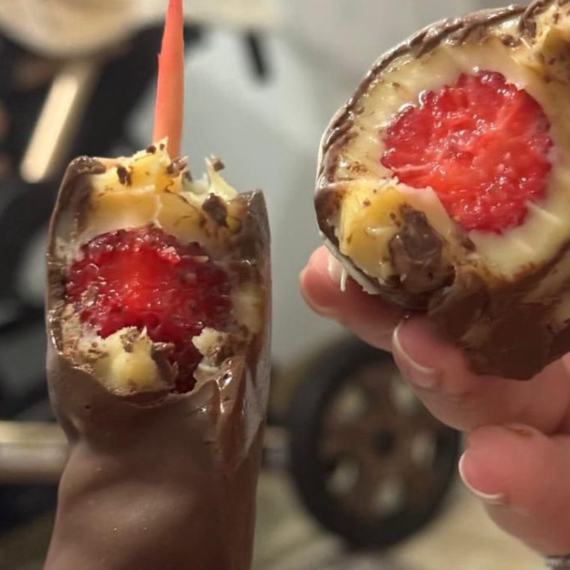 Cinco morangos no espetos cobertos com brigadeiro de ninho e casca de chocolate Blend