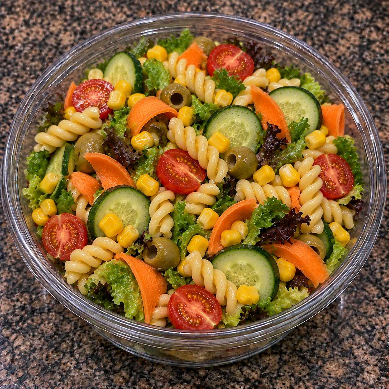 Macarrão com tomate-cereja, milho, cenoura, pepino, azeitona e folhas frescas em uma combinação leve e deliciosa.
