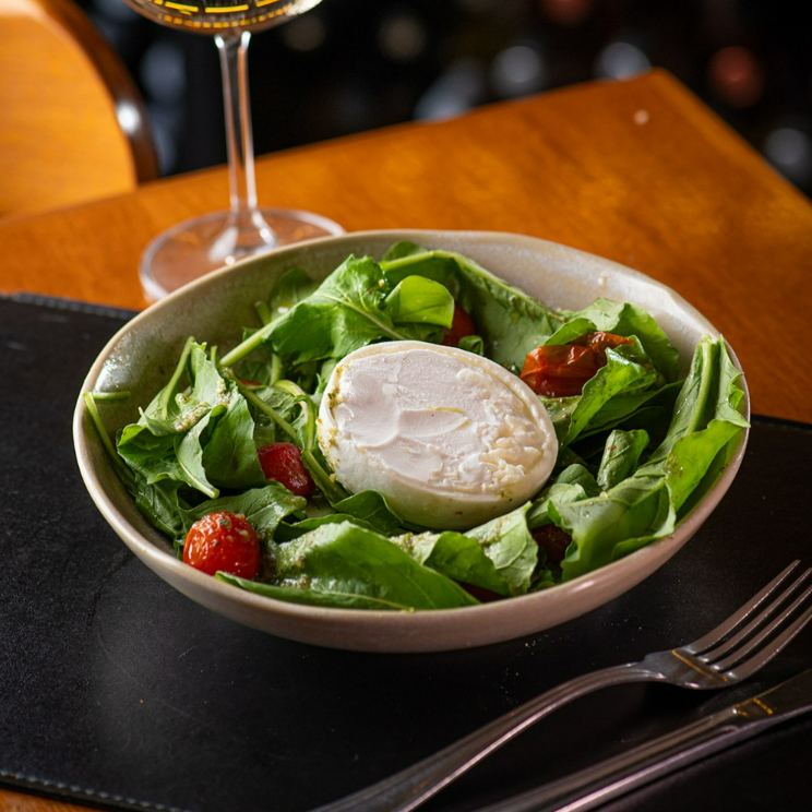 Rúcula fresca, tomates confit e burrata cremosa finalizada com azeite extravirgem