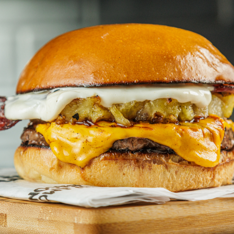 Blend bovino 150g, pão artesanal, 2 saborosas fatias de queijo cheddar, deliciosos bacon, abacaxi caramelizado e maionese farini.