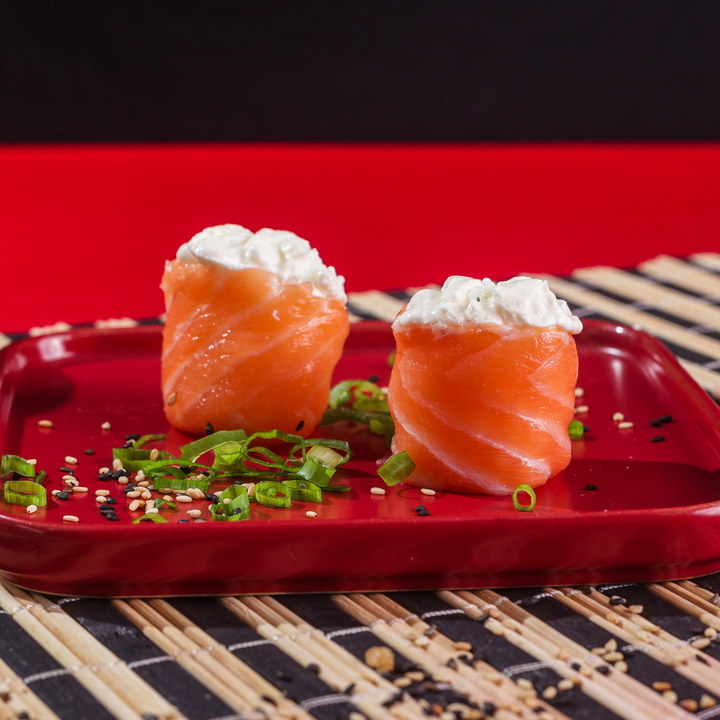 Lamina de salmão envolvendo o arroz com uma pasta de salmão com cream chesse na superfície.