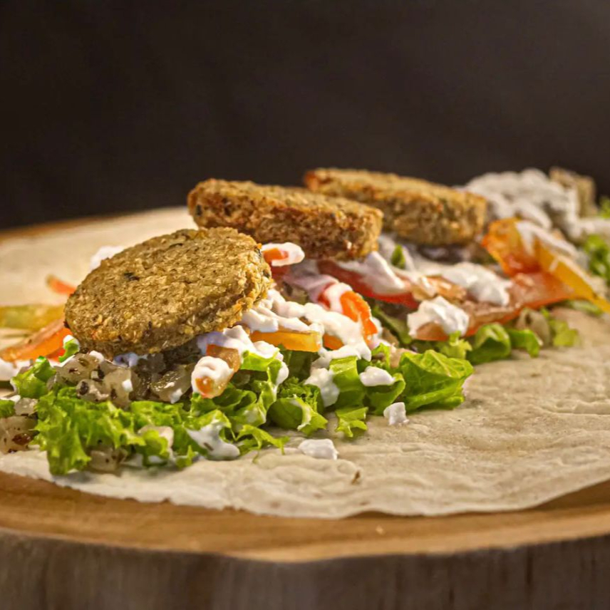 Pão sírio de 25cm recheado com falafel, alface fresco, tomate maduro e cebola temperada. Acompanha molho de alho caseiro e homus.