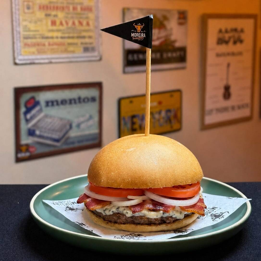 Suculento Burger Angus, Creme de Blue Cheese (Gorgonzola), Bacon Crocante, Cebola Crua, Tomate, Maionese. Servido no Pão Levemente Selado