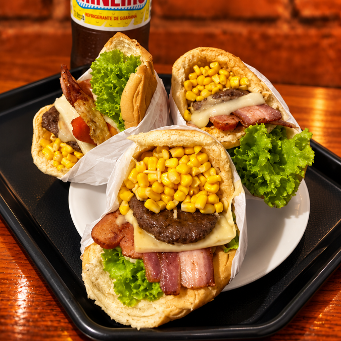 3 X-Tudo (pão, burguer, queijo, presunto, bacon, ovo, salsicha, milho, batata, abacaxi e salada), acompanhados de 1 refrigerante Mineiro 2L. Uma combinação caprichada para dividir e saborear!