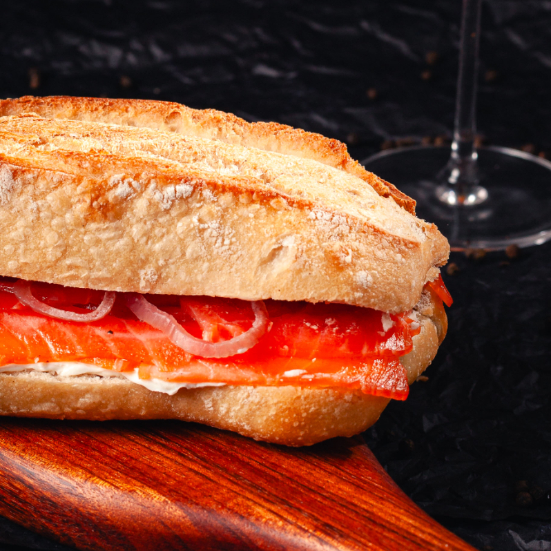 Sanduiche com salmão fatiado, pão ciabatta, picles de cebola, rúcula e molho