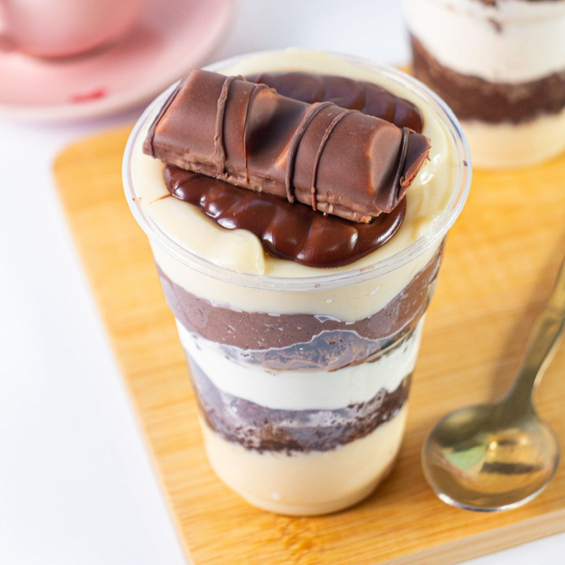 Um delicioso copo da feicidade com brownie, bolo de chocolate, brigadeiro branco, mousse de ninho e chocolate 50% cacau finalizado com Nutella e Kinder bueno servindo muito bem 1 pessoa, 200ml.
