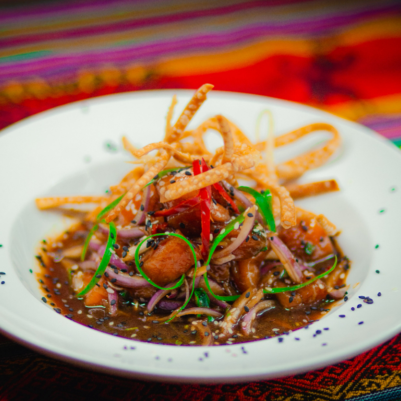 Ceviche no leite de tigre ao molho shoyu, gergerlim cebolinha, óleo de gergerlin e pimenta. Acompanha massa de pastel finamente cortado