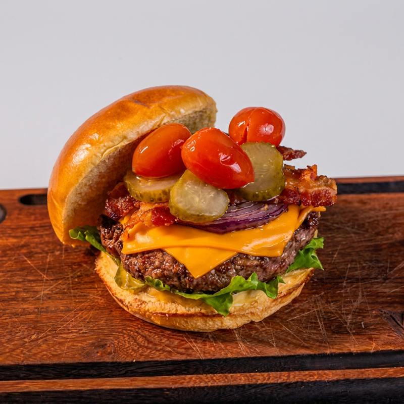 Carne grelhada (200g), alface americana fresca, cebola grelhada, tomate suculento, picles, queijo derretido, muito bacon e pão artesanal.