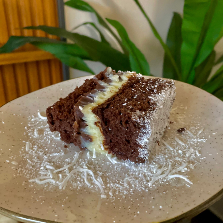 Delicioso bolo gelado com massa de chocolate macia e molhadinha, recheado com brigadeiro cremoso e creme de coco. Finalizado com uma cobertura de brigadeiro, trazendo a combinação clássica e irresistível de chocolate com coco. Perfeito para quem ama um doce bem cremoso e equilibrado!