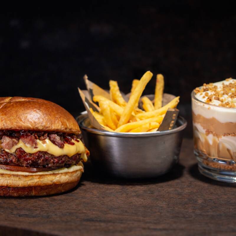 01 Hambúrguer Boom Bacon: Pão especial selado na manteiga, Burger bovino 160g, Creme cheddar (feito na casa), Tomate, Bacon Artesanal, Maionese defumada de ervas (feita na casa), geleia de cebola caramelizada. 1 Batata P (100g), quentinha, crocante e sequinha. 1 Sobremesa, escolha sua favorita!