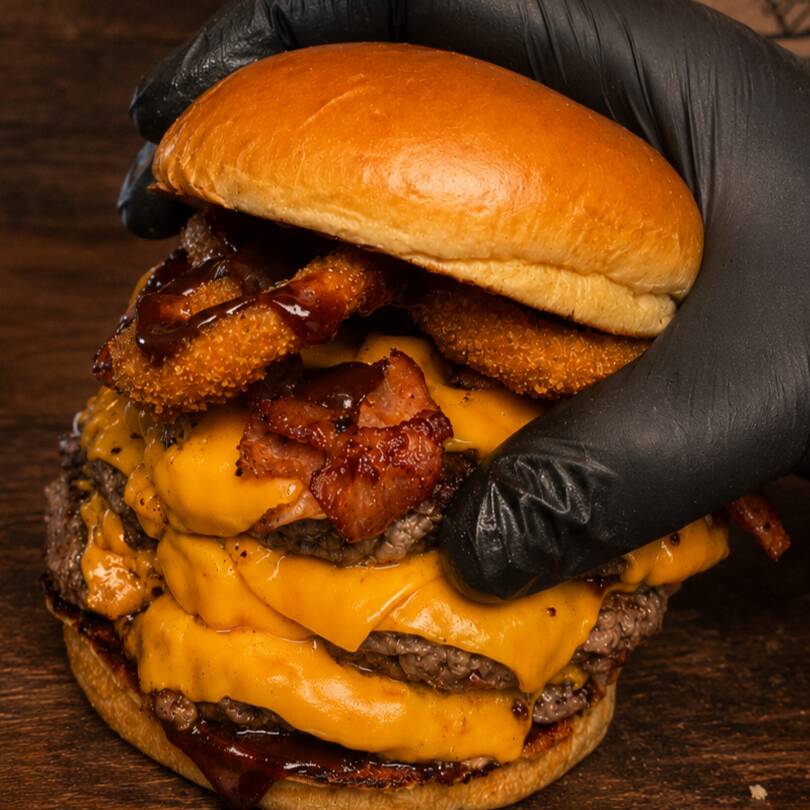 Pão brioche tostado, três smash burgers de 80g com crosta bem marcada na chapa, cheddar fatiado derretendo em camadas, bacon crocante, cebola empanada e barbecue defumado. O burguer é feito no ato do pedido, chegando quentinho e saboroso!