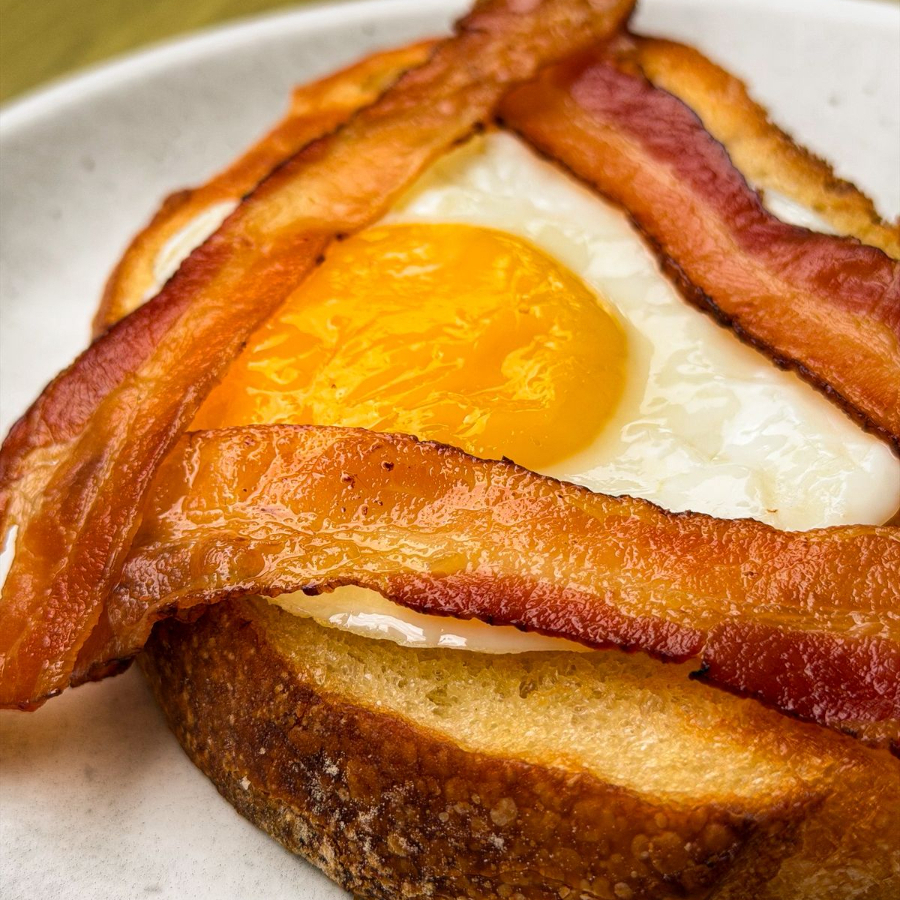 Pão italiano, com manteiga, bacon, e ovo com gema mole.