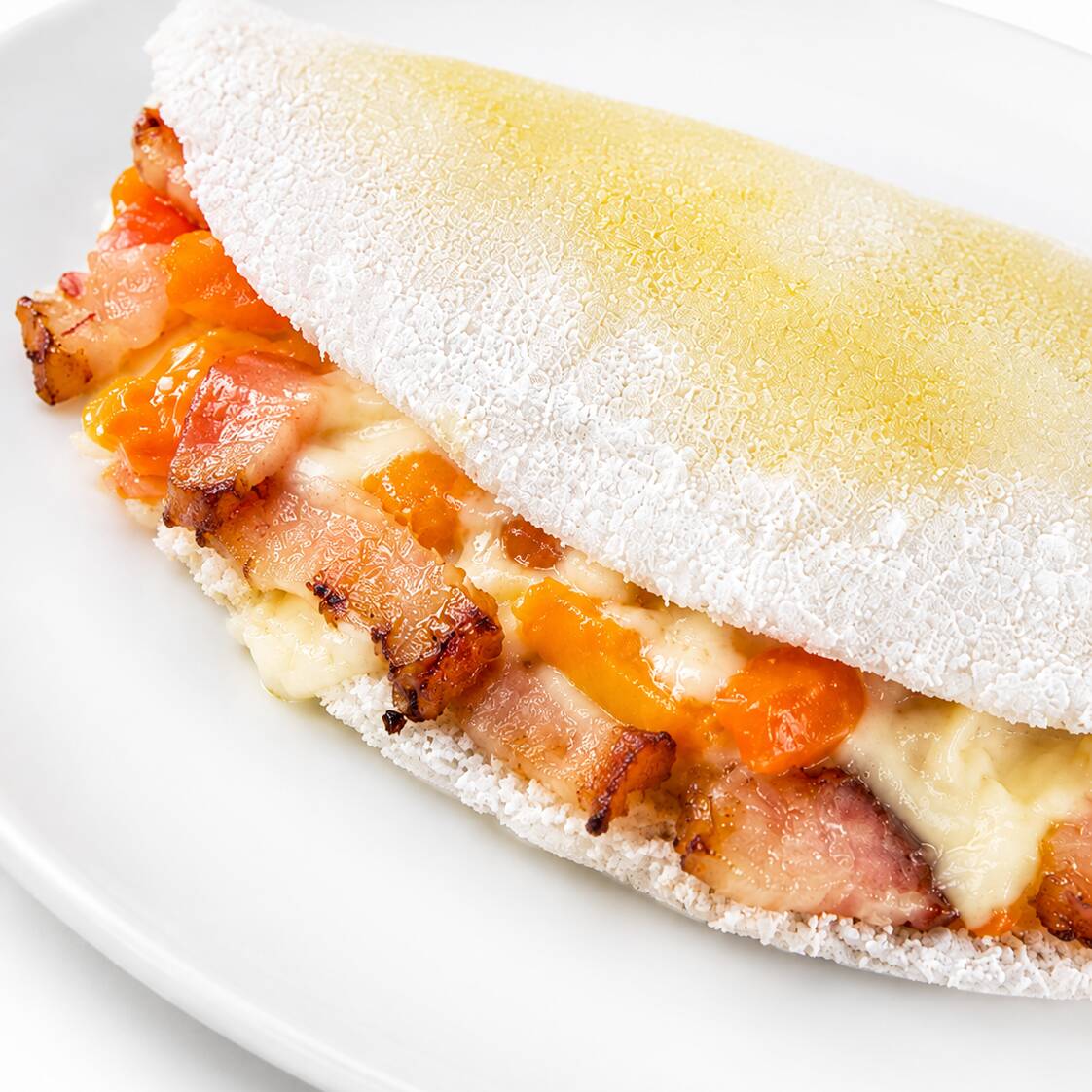 Tapioca recheada com bacon fatiado, muçarela e fatia cheddar cremoso derretido.
